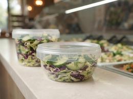 Salad in a clear shallow 385 ml container on a deli counter