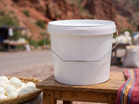 2.3 升白色带盖塑料桶，配金属提手，放在博姆峡谷（Boom Gorge）路边的小桌上，旁边是一盘奶疙瘩（kurt）球