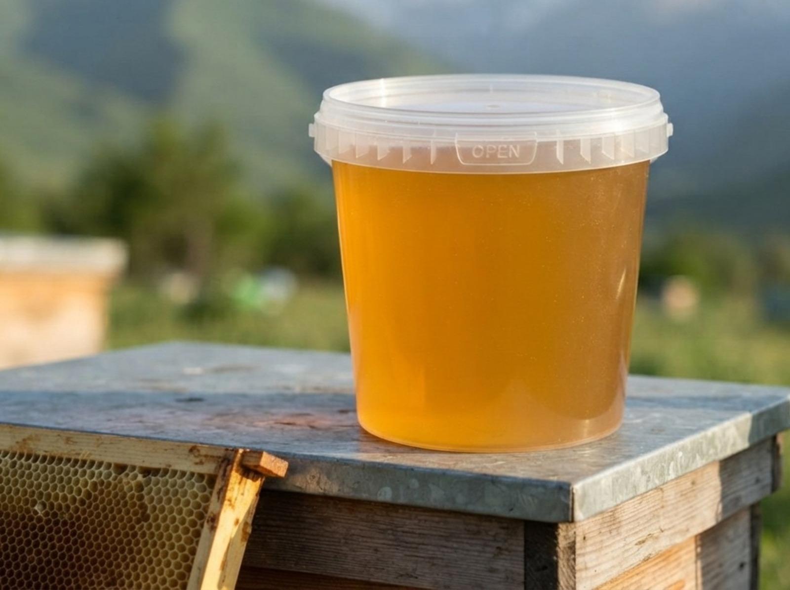 梅尔克附近吉尔吉斯山脉山麓的蜂场里，蜂箱顶上放着一只装着蜂蜜的 1 升透明带盖塑料桶