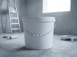 18 liter plastic bucket of white paint with a roller on a building site