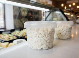 Cottage cheese in a clear 550 ml plastic container on a deli counter