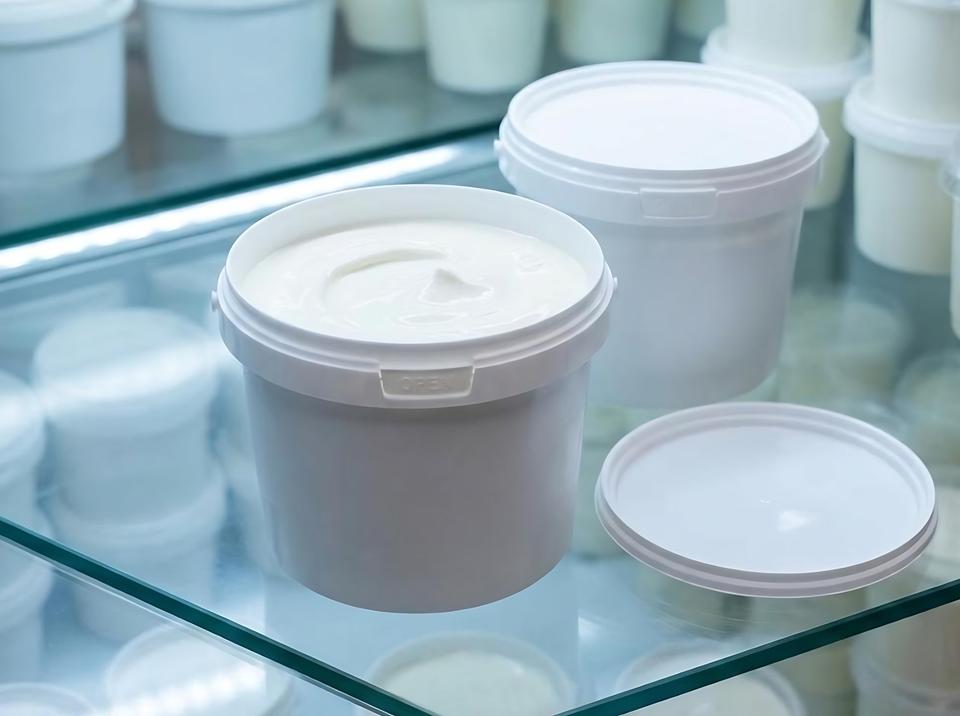 Sour cream in a white 800 ml plastic bucket in a refrigerated shop display