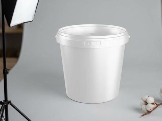 White 1 L plastic bucket with lid against a light background in an online store's photo corner next to a cotton branch