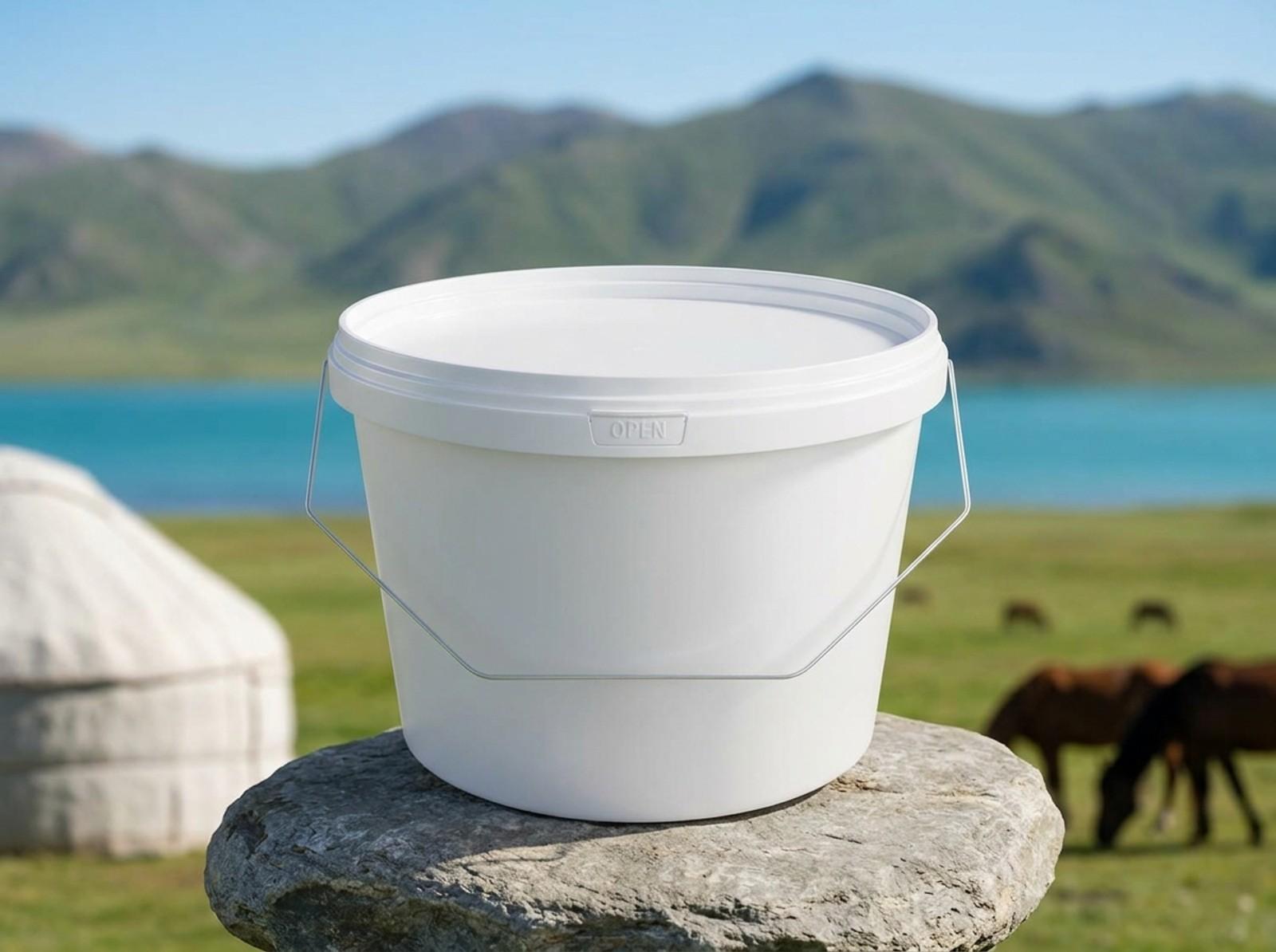 White 3 L plastic bucket with lid and metal bail handle on a flat stone by a yurt on a jailoo at Lake Son-Kul