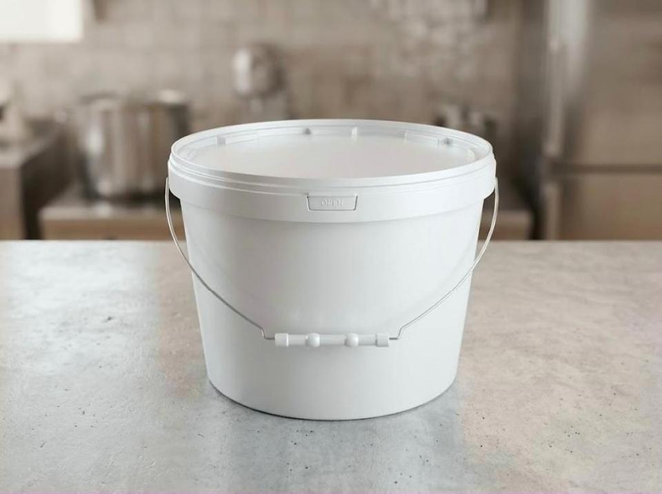 White 8 liter plastic bucket on a concrete worktop in a food prep kitchen