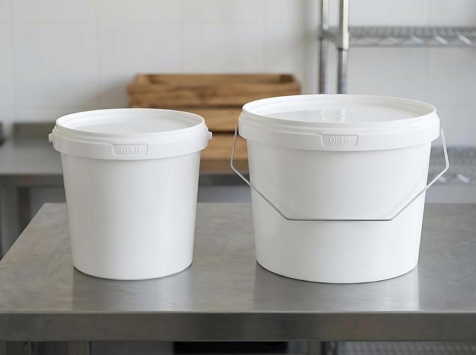 1 and 2.3 liter plastic buckets side by side on a workshop table