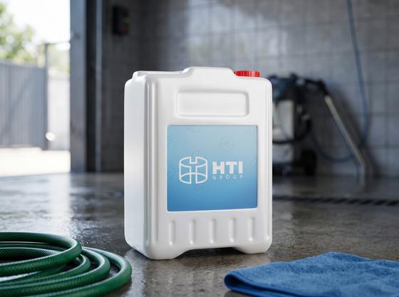 White 10 L plastic jerry can with a cap on the wet concrete floor of a car wash in Almaty next to a coiled green hose