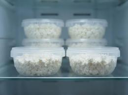 Shallow 385 ml plastic containers with cottage cheese in a store's refrigerated display case