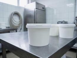 White 800 ml plastic bucket with the lid closed on a table in a dairy plant