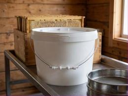 8 liter plastic bucket of honey in an apiary extracting room
