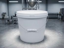 White 18 liter plastic bucket with a steel bail handle and lid on the concrete floor of a production hall