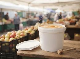 5.6 liter plastic bucket of honey on the counter of a farm shop